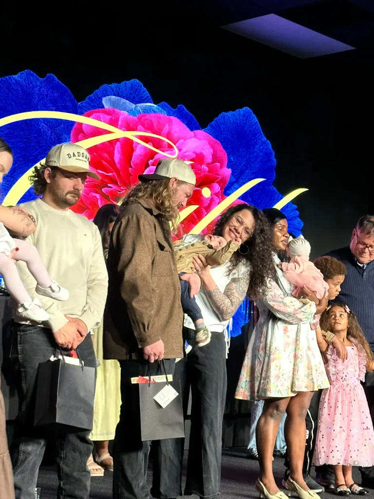 Groups of parents dedicating their children on stage during a worship service