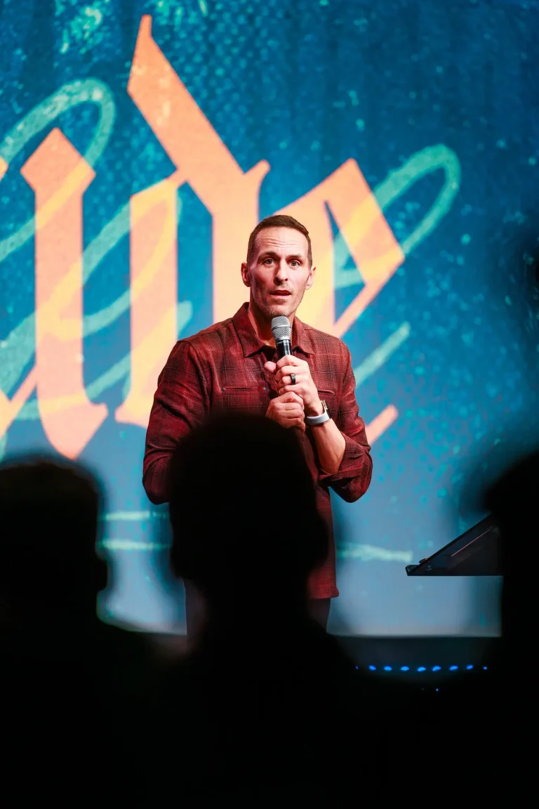 Pastor Jared Fabac speaking into a microphone in front of a large LED screen