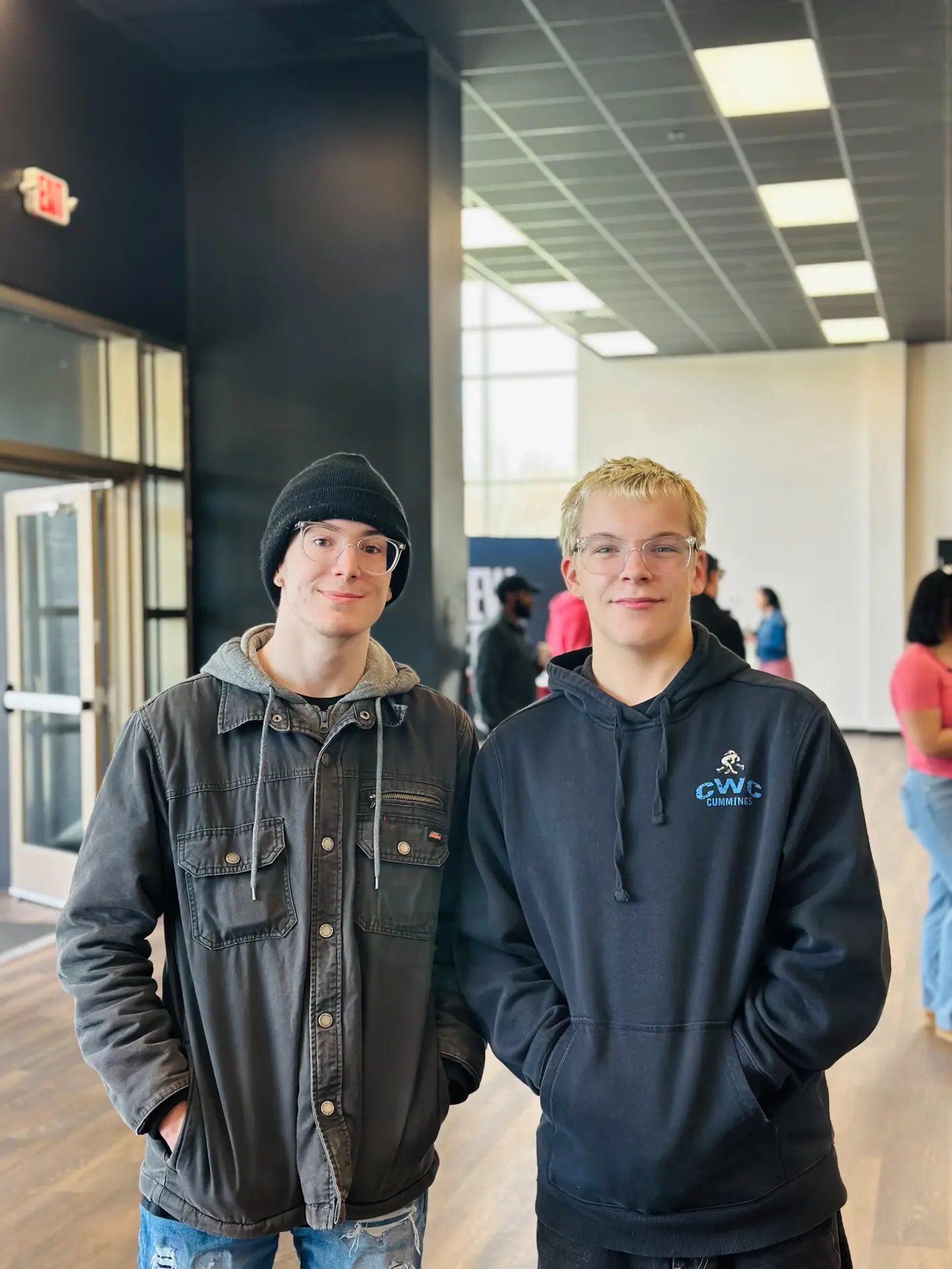 Two young men stand next to each other in the church lobby