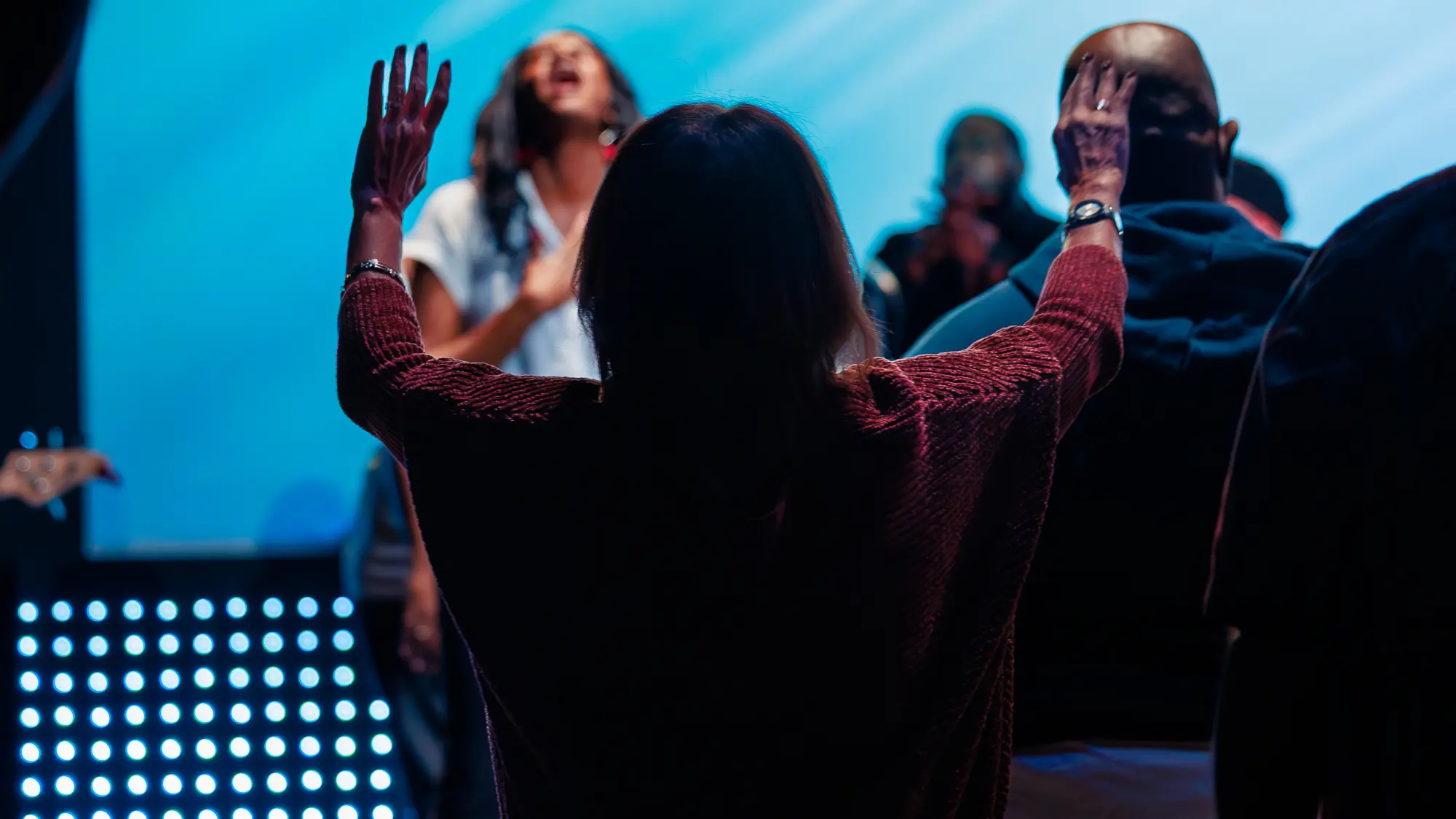 A woman with her arms raised during a worship service