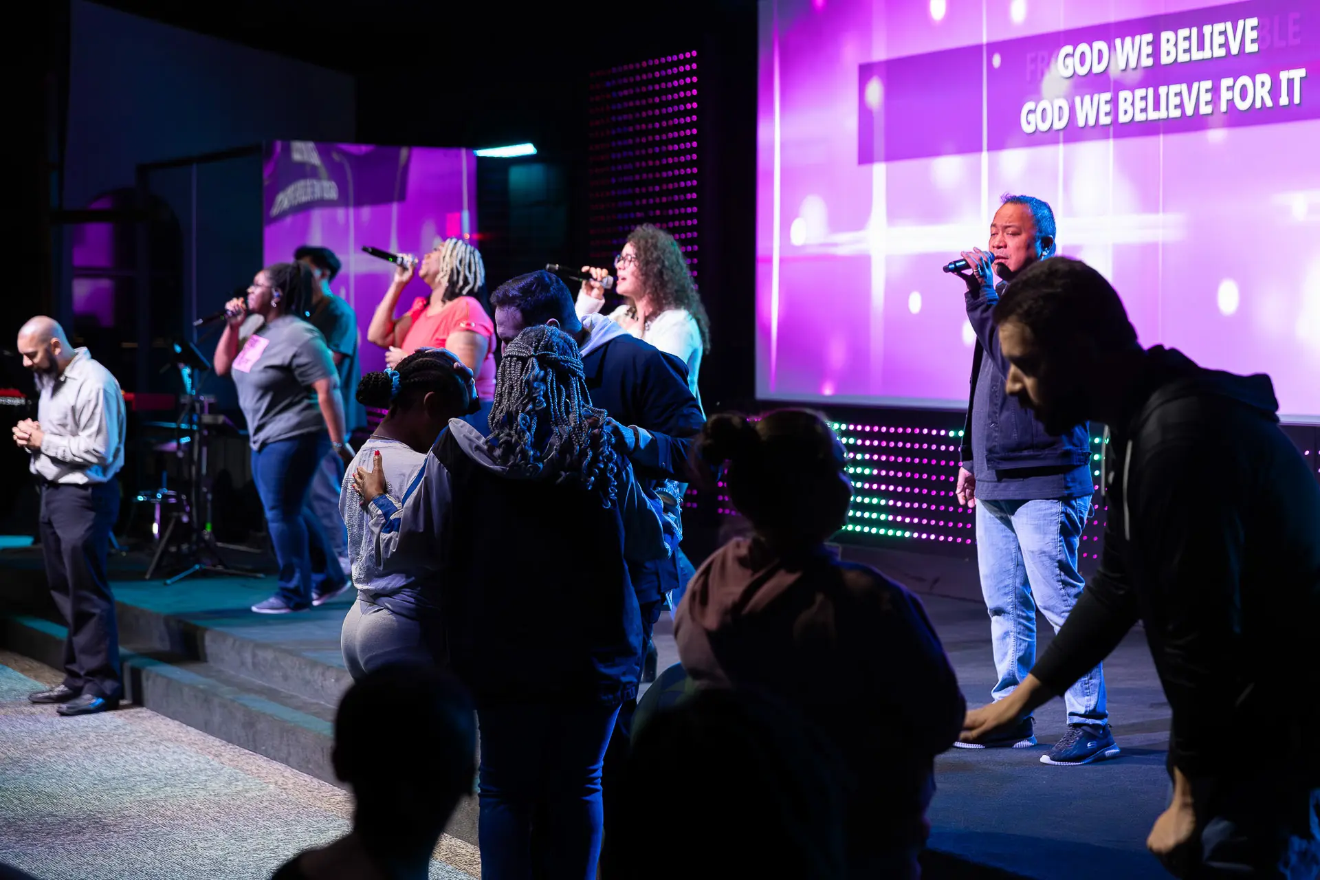 Jared Fabac, the pastor, praying with two women during a worship service