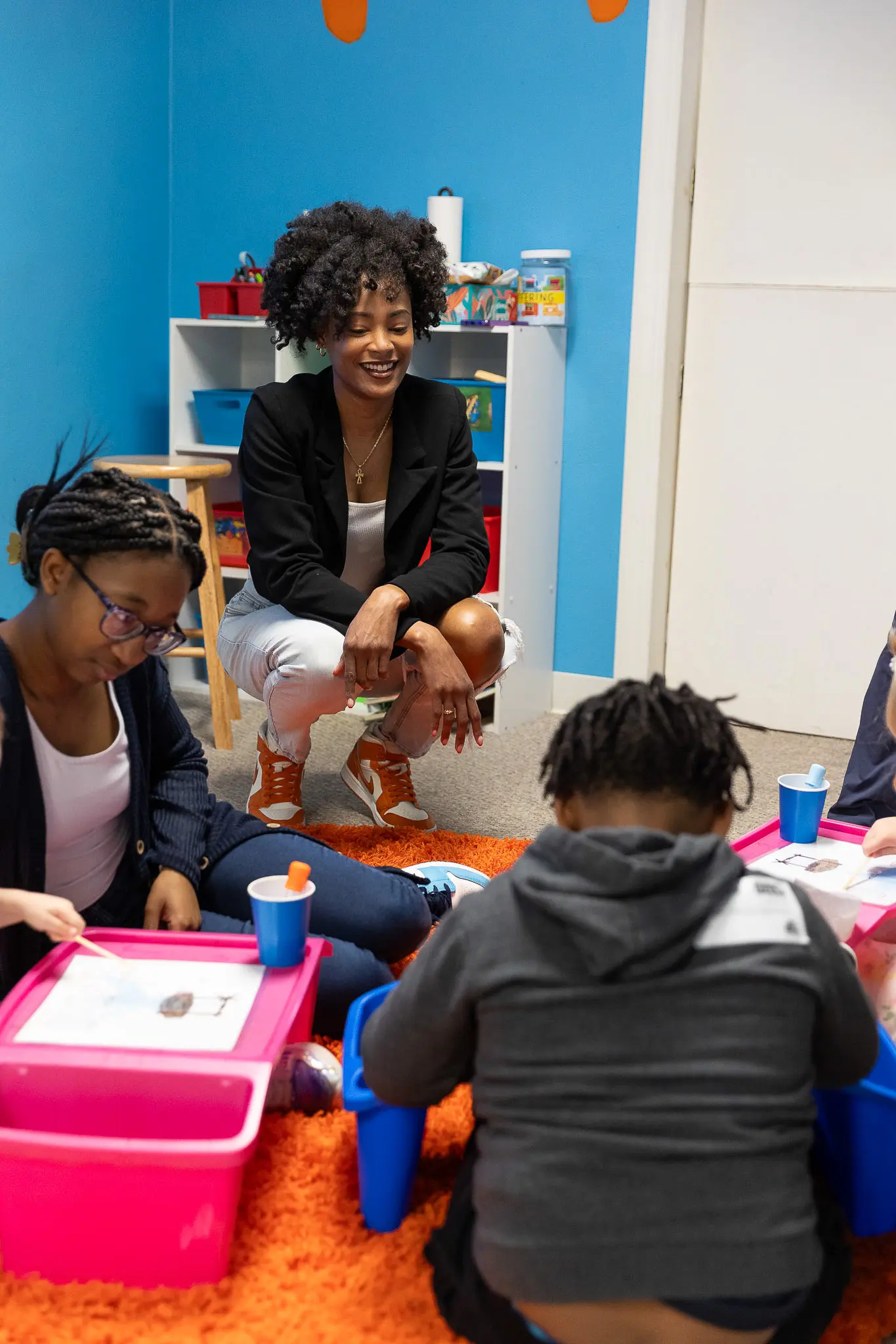 A kids ministry volunteer crouched next to some kids doing crafts